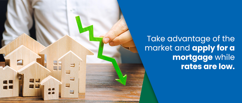 Take advantage of the market and apply for a mortgage while rates are low - Image of  wooden houses and a green downward facing arrow signifying lower rates