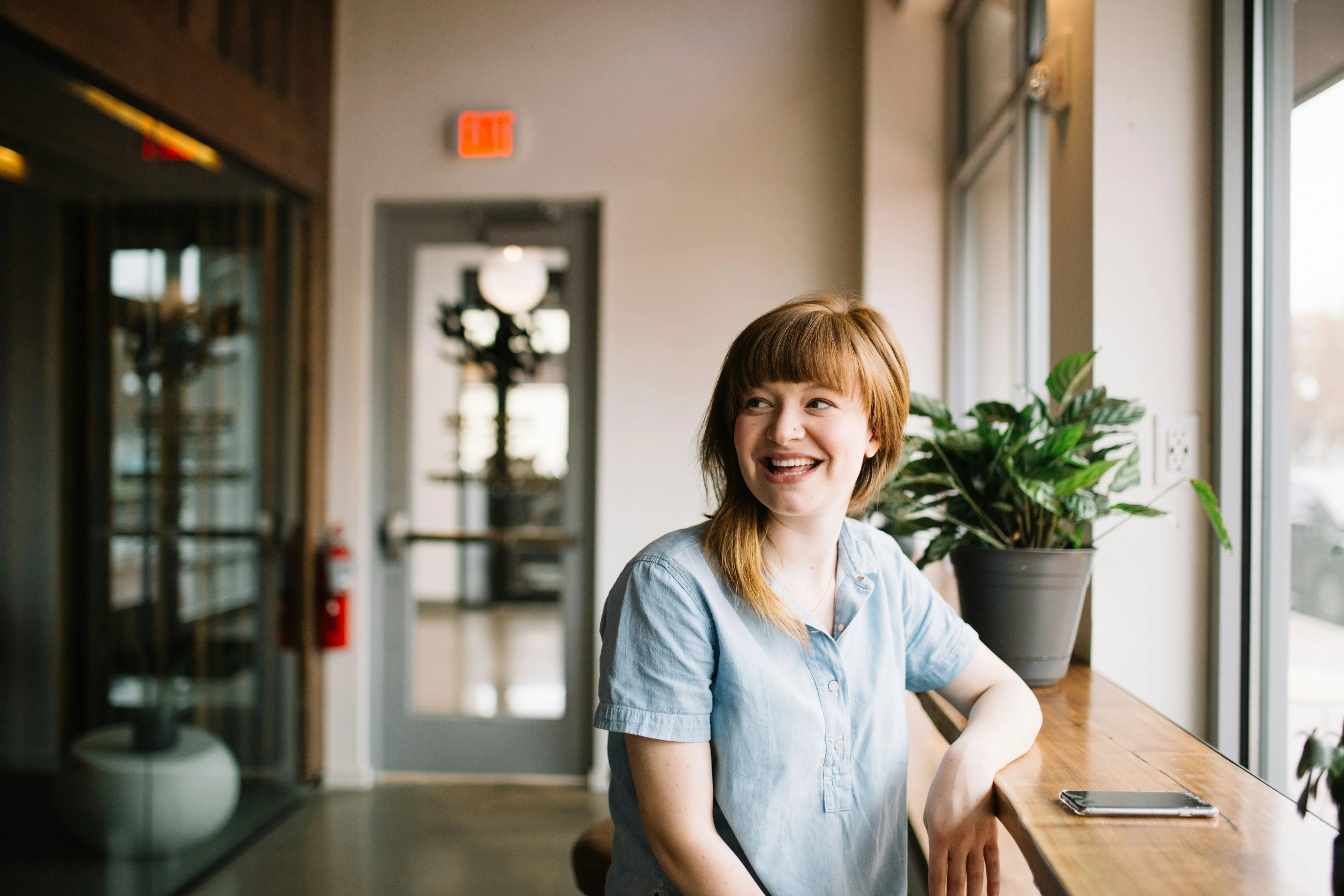 A young woman smiles brightly while sitting in a cafe, feeling confident as she opens a certificate account with her new york credit union