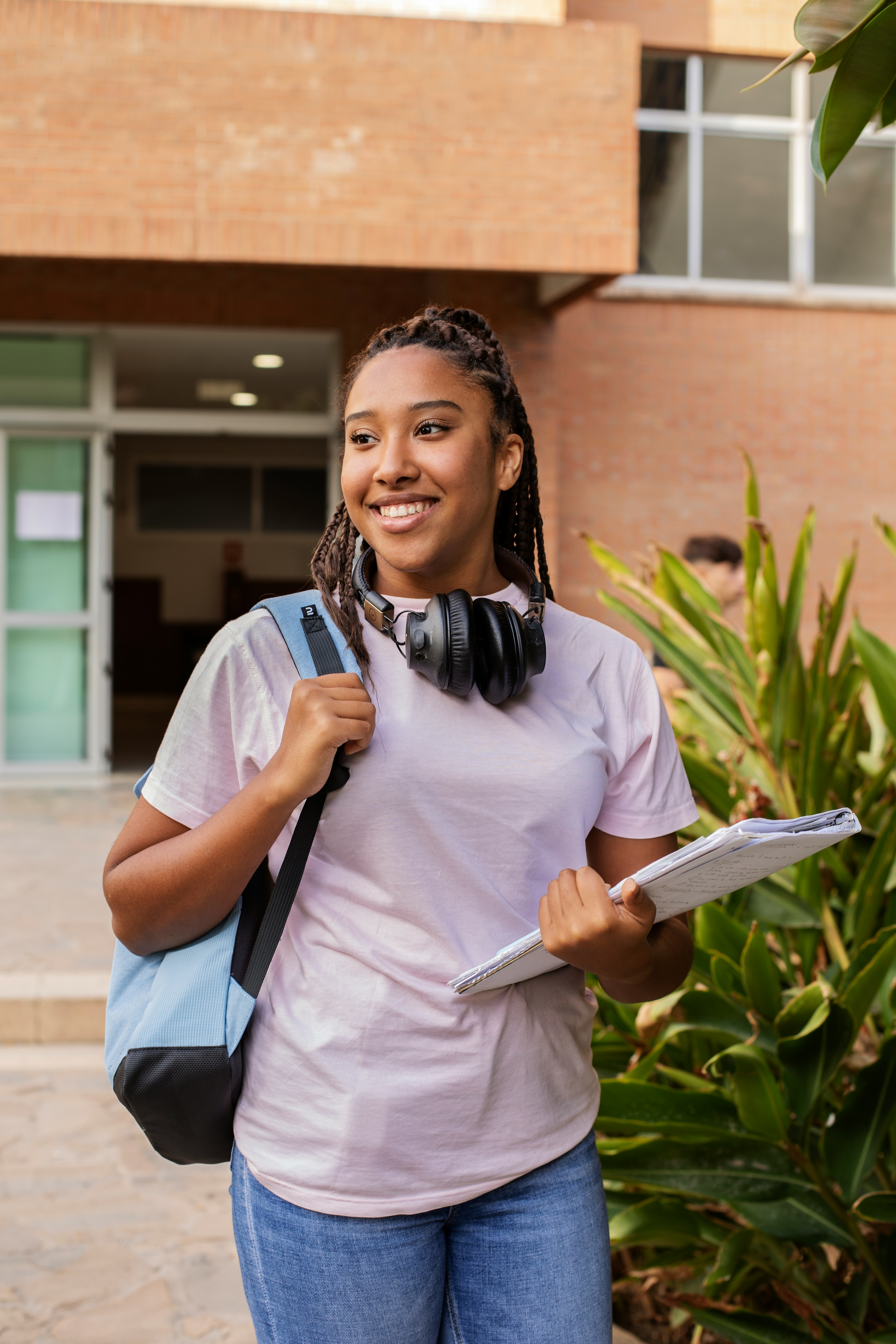 A smiling student leaving school - ready to open a student loan with her New York credit union.